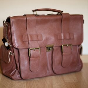 Stylish brown leather satchel on wooden flooring, perfect for travel or business.