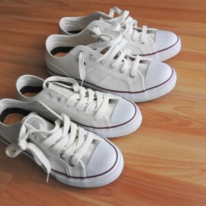 Pair of white sneakers on a clean wooden floor, casual and sporty look.