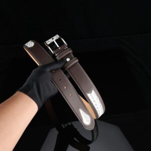 Stylish brown leather belt with silver detailing held by a gloved hand.