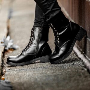 Black leather boots worn on a street sidewalk, displaying edgy fashion style.